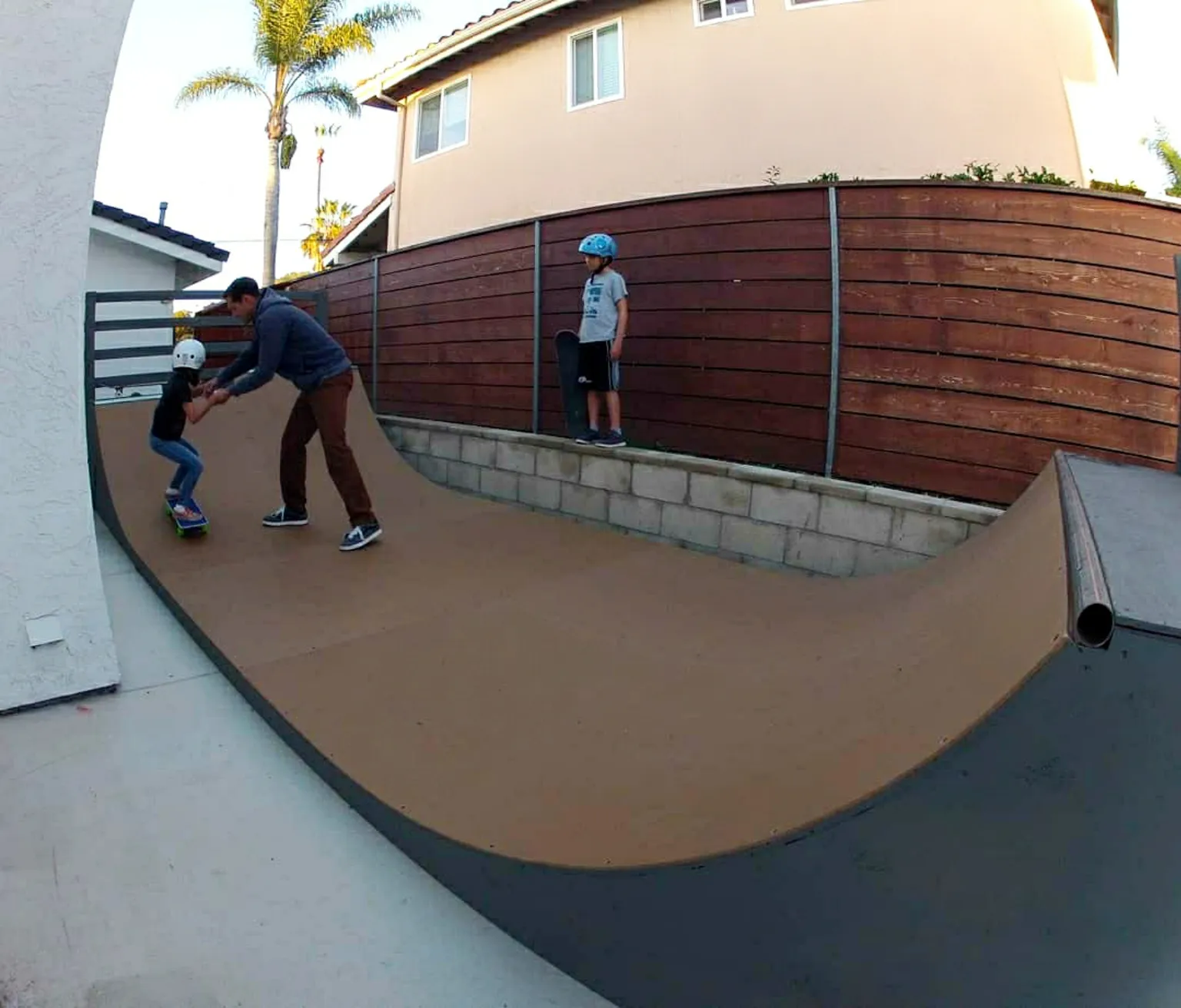 Three foot high miniramp in small side yard with kid being trained by adult