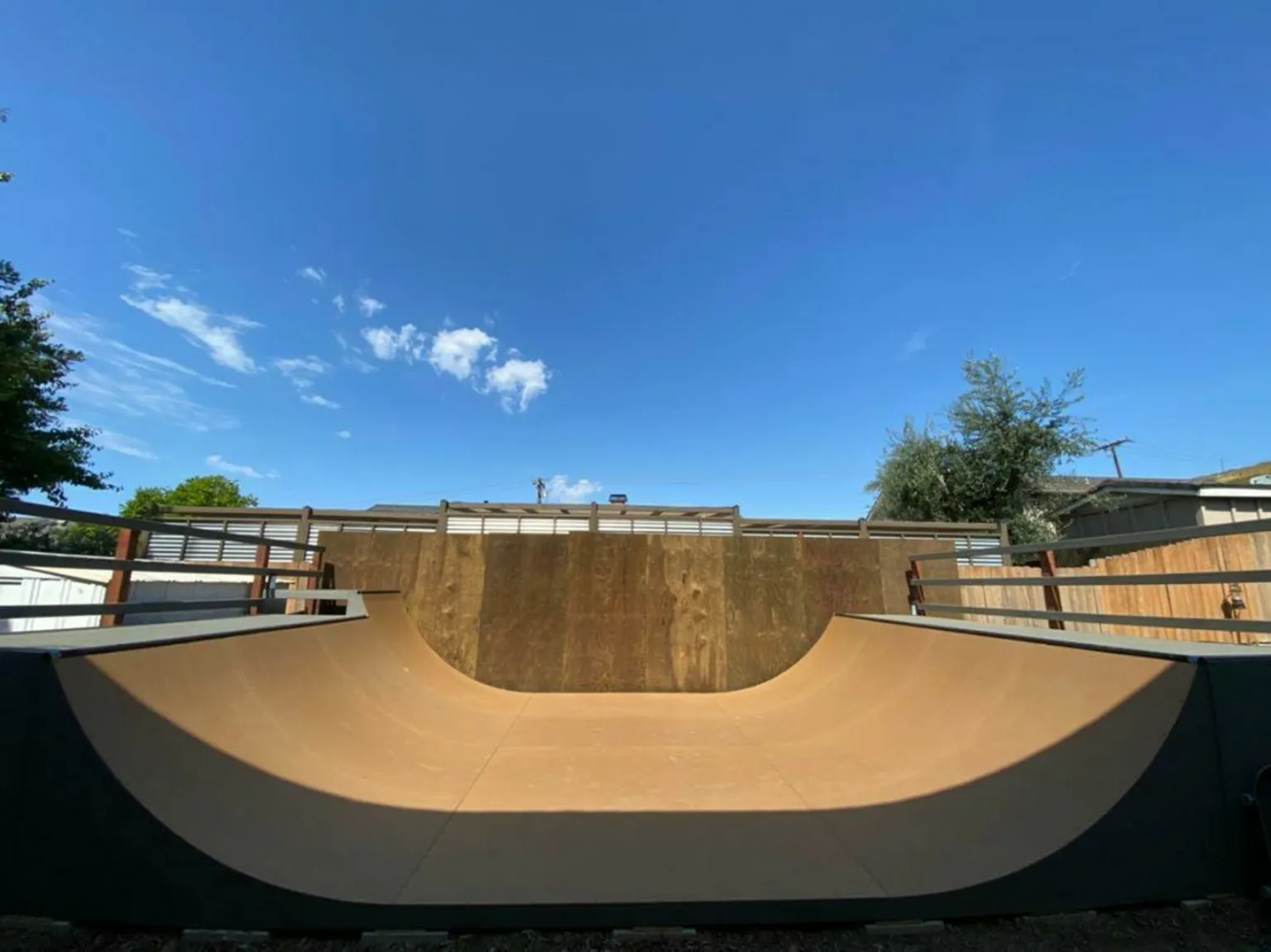 Four foot high miniramp in large yard with blue sky backdrop