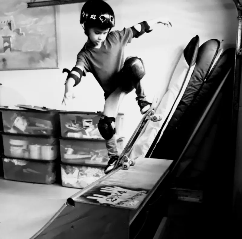 Black and white photo of Original 2x4 miniramp with young kid doing a blunt stall