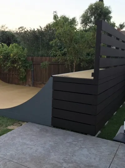 Left side view of miniramp with deck, side, and back cover with horizontal panels in a dark paint