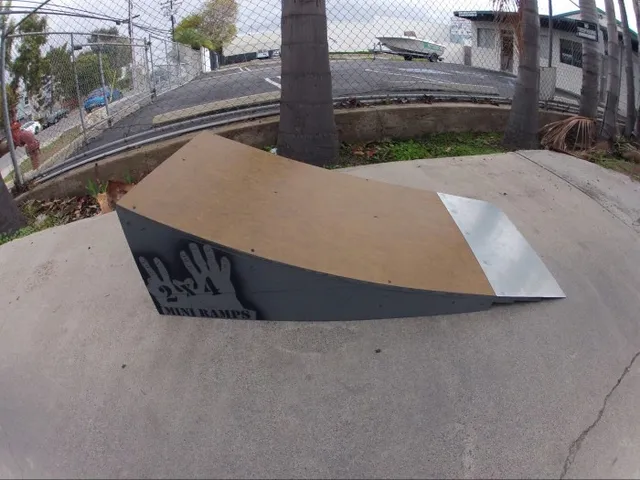 Two foot high launch ramp by fence  near palm tree on concrete, size view