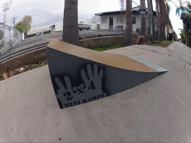Two foot high launch ramp by fence  near palm tree on concrete, secondary angle